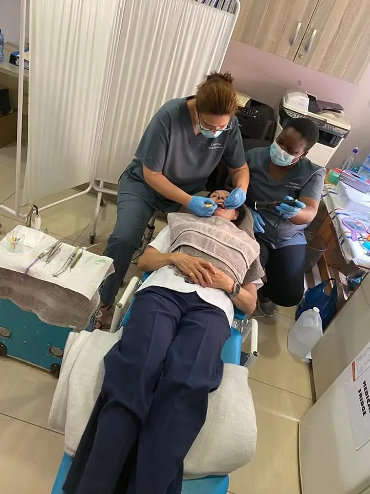 Two dental hygienists performing mobile dental treatment on a patient